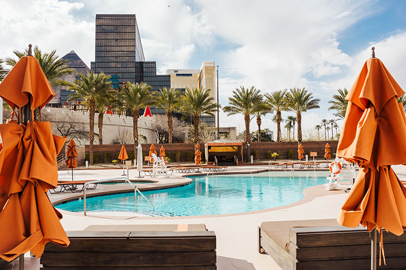 A beautiful pool and patio at a Las Vegas Hotel Resort. High Rise building and palm trees in the background